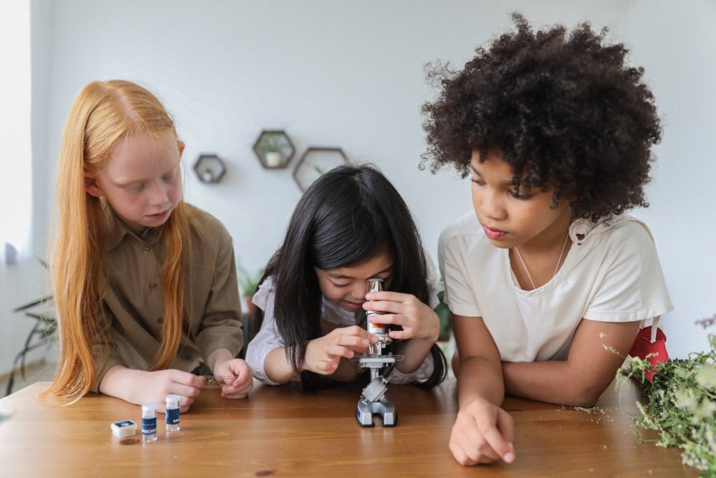 trzy dziewczynki korzystają z mikroskopu dla dzieci