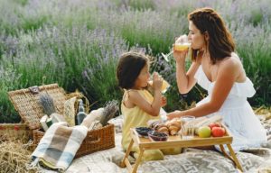 mama z córeczką siedzą na beżowo białym kocu piknikowym